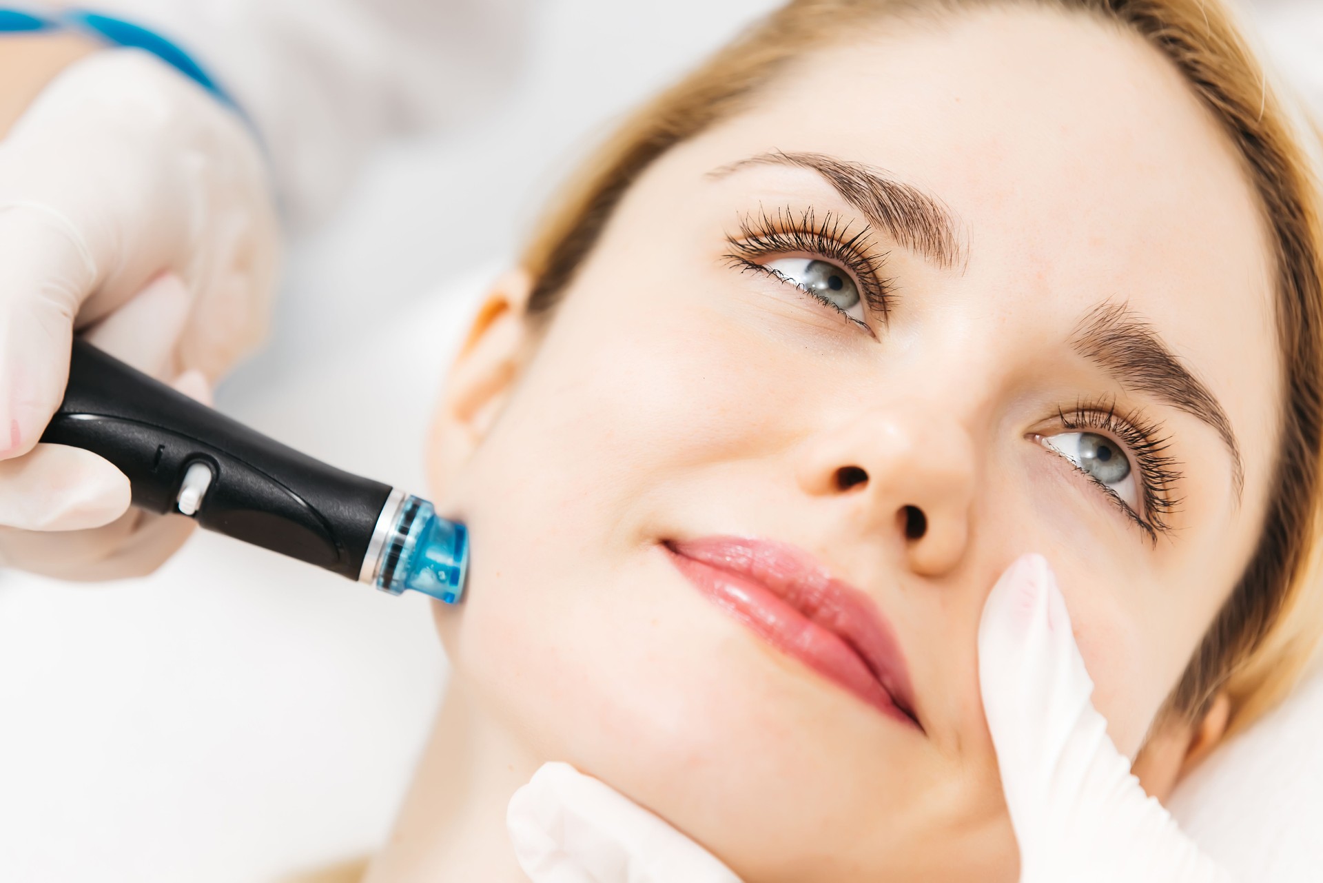 A professional cosmetologist performs hydropeeling and Hydradermabrasian on the client, providing advanced skin care procedures. Ideal for promoting luxury beauty services and enhancing your brand image.